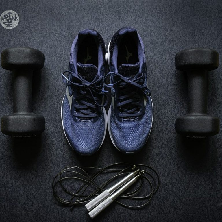 Personal Training & Sporttherapie Sportschuhe mit zwei Kurzhanteln und einem Springseil auf einer Sportmatte